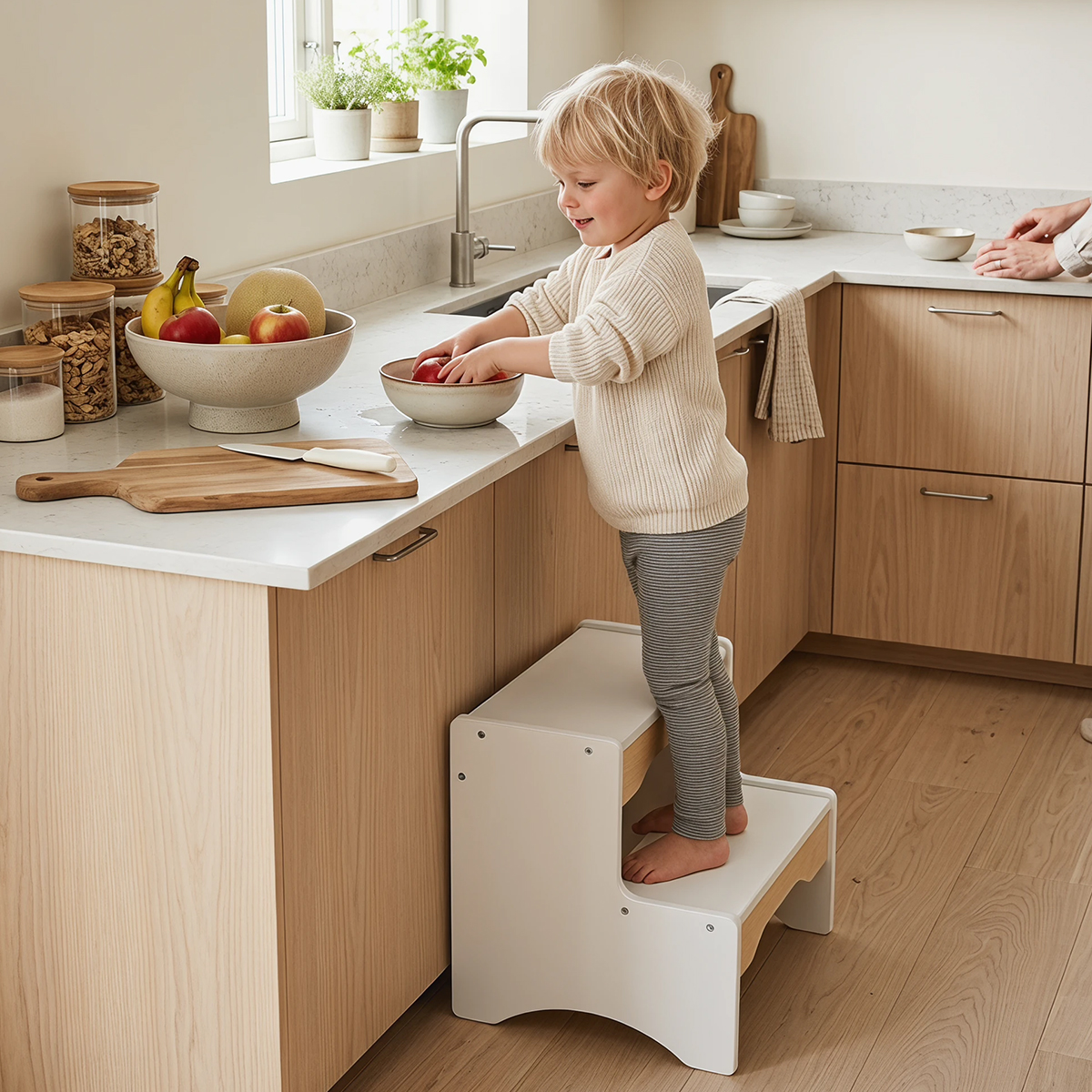 Toddler standing on white and natural wood 2-step stool in kitchen