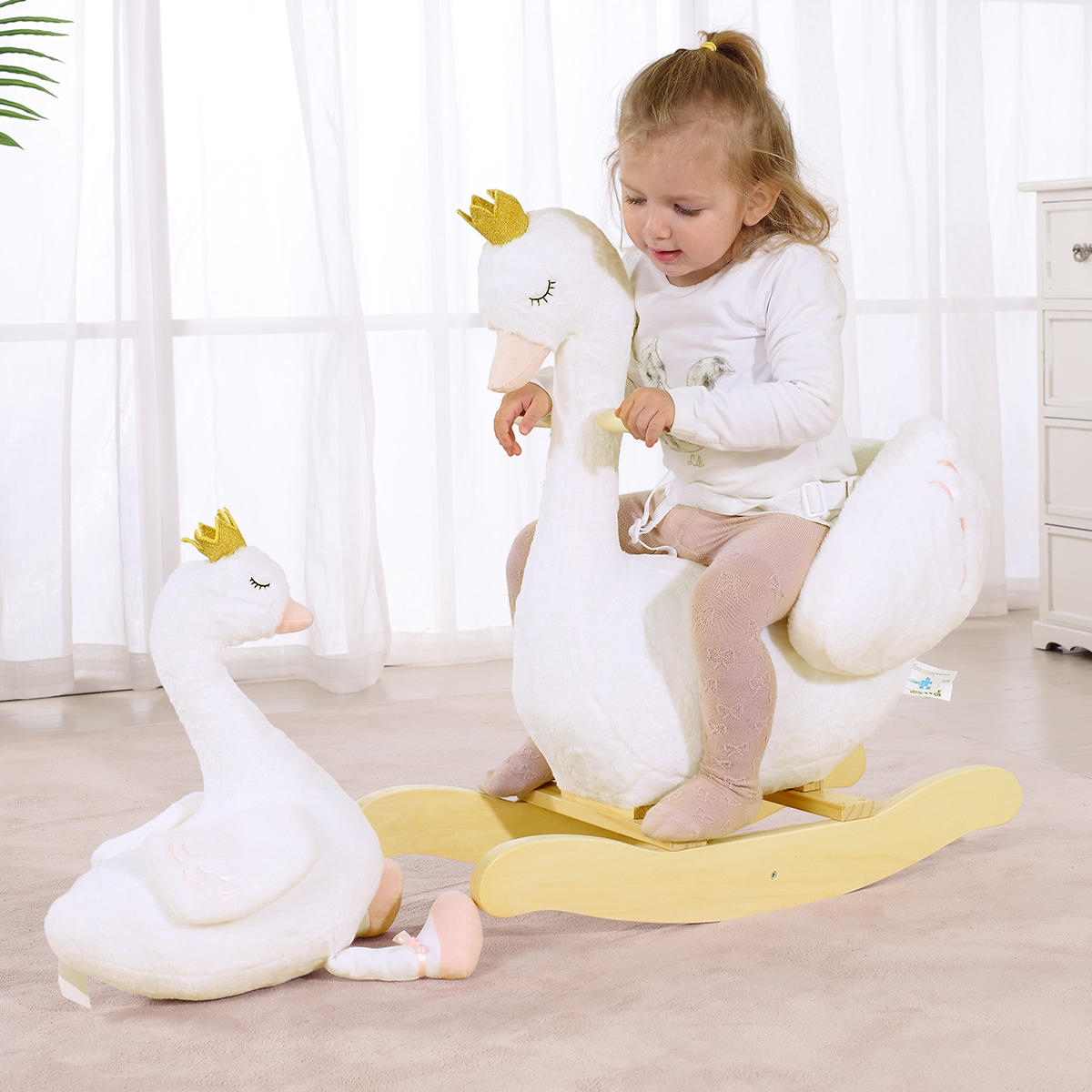 Toddler riding white swan plush rocker with matching swan toy
