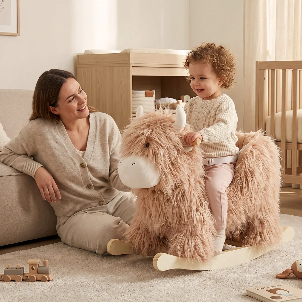 Toddler riding a yak plush rocking horse with parent