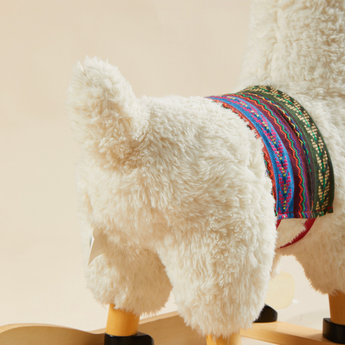 Close-up of plush llama rocker fabric and colorful saddle detail
