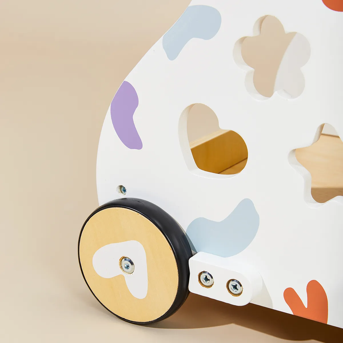 Side view close-up of wooden baby walker with shape sorter cutouts and silent wheel