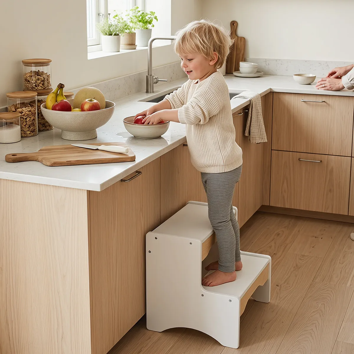 Child standing on wooden 2 step stool helping at kitchen counter